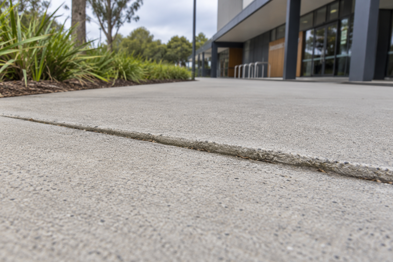 Close-up of a raised concrete footpath joint from a low angle